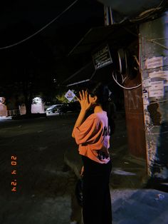 a woman standing on the side of a road holding her hand up to her face