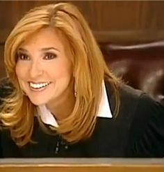 a woman sitting at a desk with a laptop computer in front of her and smiling