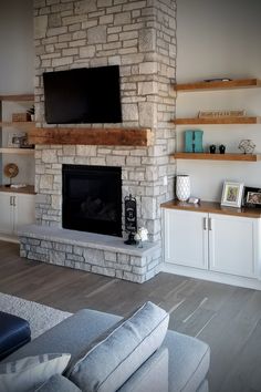 a living room with a large stone fireplace and shelves on either side of the fire place