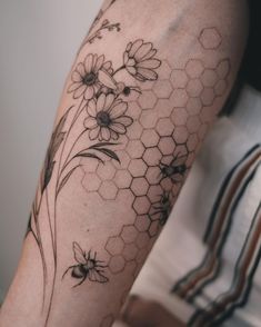 a woman's arm with flowers and honeycombs on it