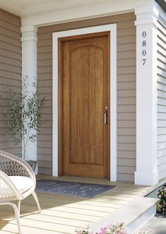 a white chair sitting in front of a wooden door on a house's porch