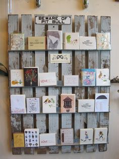 a wooden pallet with pictures and magnets attached to the side, mounted on a wall