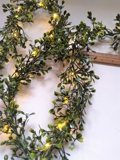 a wreath made out of branches with lights on it and a piece of wood in the background