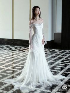 a woman in a white dress standing on a tiled floor