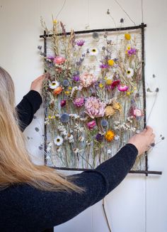 a woman is working on an art piece with flowers in the middle and behind her