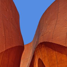 an orange building with wavy lines on it's side and a blue sky in the background