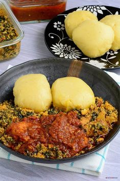 some food is in a black bowl on a table with other dishes and utensils