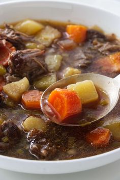 a spoon full of beef stew with carrots and potatoes