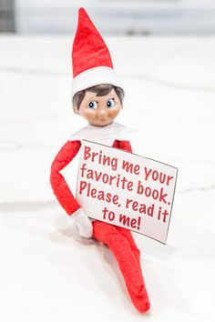 an elf holding a sign that says bring me your favorite book please, read it to me