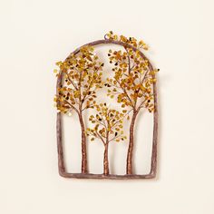 a metal wall hanging with trees and leaves in the shape of an arch on a white background