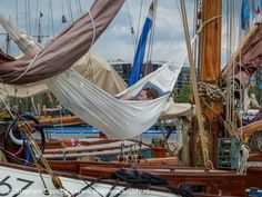 there are many sailboats docked at the harbor with one man sleeping in a hammock