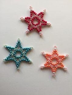 three beaded stars on a white surface