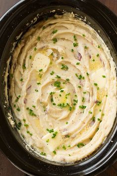 a black bowl filled with mashed potatoes on top of a wooden table