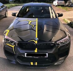 a black car with yellow stripes parked in a parking lot