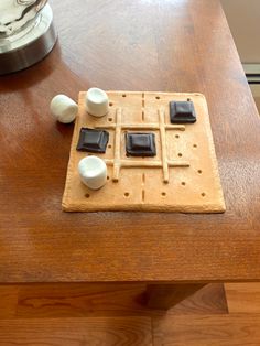 a wooden table topped with a game board and pieces of black and white marbles