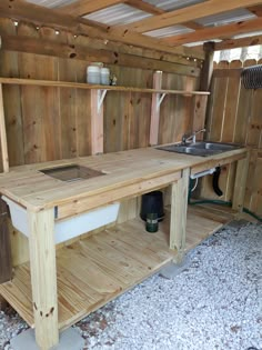 an outdoor kitchen with wooden walls and shelves on the wall, in front of a sink