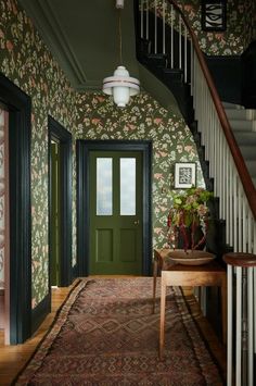 the hallway is decorated with wallpaper and rugs, along with a green door