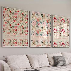 three flower market posters hanging on the wall above a white couch in a living room