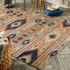 an area rug with blue and orange colors on the floor next to a basket full of books