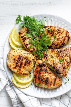 grilled chicken with lemons and parsley on a white plate