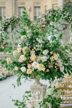 a vase filled with lots of flowers sitting on top of a table next to chairs