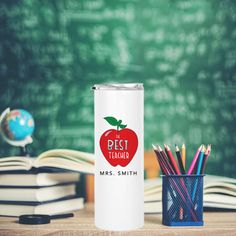 a white can with the words best teacher on it next to books and pencils