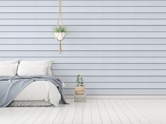 a bedroom with blue walls and white bedding, hanging planter on the wall