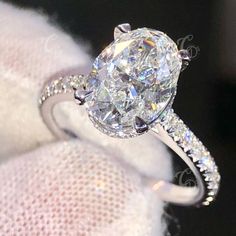 an oval cut diamond engagement ring with pave set diamonds on the band and side stones