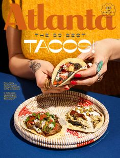 a woman holding a taco on top of a plate