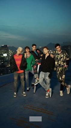 group of young men standing on top of a building with city lights in the background