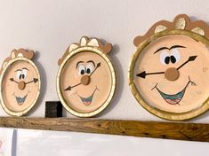 three clocks with faces painted on them hanging from the wall