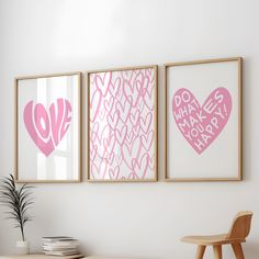 three pink hearts are hanging on the wall next to a wooden table with a potted plant