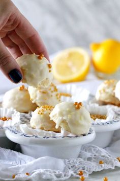 a person picking up some food from a white plate with lemons in the background