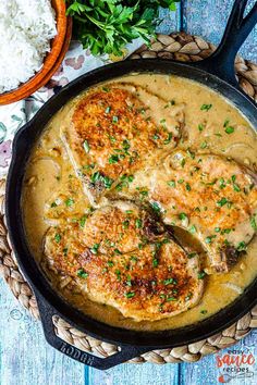 chicken chops with gravy in a skillet next to rice and parsley