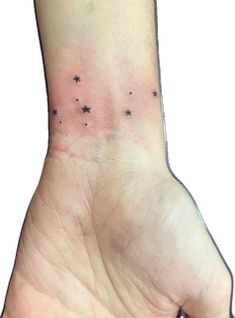 a person's hand with small black stars on the left side of their wrist