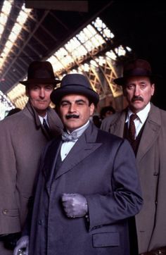 three men in suits and hats are posing for a photo with one man wearing a top hat