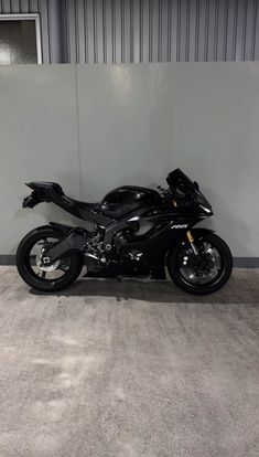 a black motorcycle parked in front of a wall