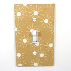 a light switch cover is shown with white dots on brown fabric, and has an intricate design