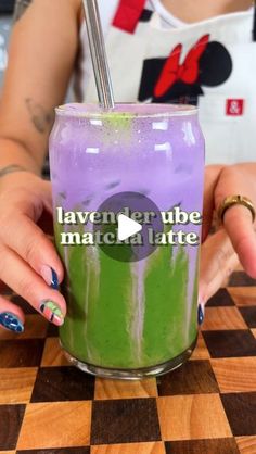 a woman holding a purple and green drink