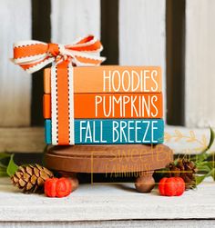 stack of books with orange and blue covers sitting on top of each other next to pine cones