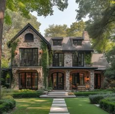 a large stone house in the middle of a lush green yard with steps leading up to it