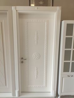 a white door is open in a room with shelves and cupboards on either side