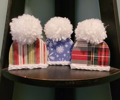 three hats with pom - poms are sitting on a shelf