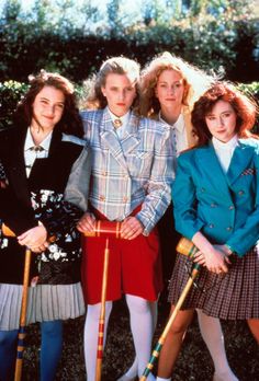 four young women standing next to each other holding croquets and canes