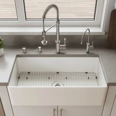 a white kitchen sink sitting under a window next to a potted plant on top of a counter