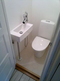 a white toilet sitting next to a sink in a bathroom under a faucet