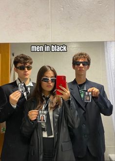 two men and a woman standing in front of a mirror taking a selfie with their cell phones