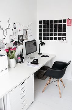 a white desk topped with a computer next to a black chair