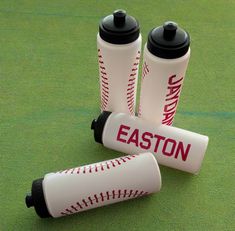 three plastic cups with baseballs on them are sitting on the ground next to each other