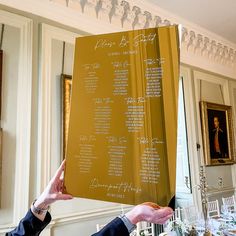 two people holding up a large menu in the middle of a room with tables and chairs